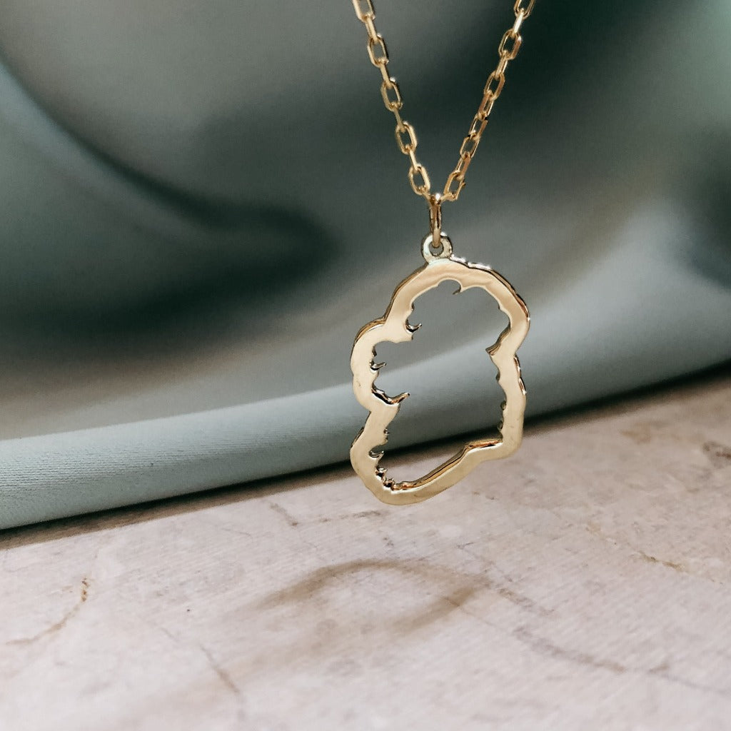 solid gold map of ireland necklace with green silk background 