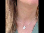 video of a woman wearing a dara knot sterling silver necklace and matching drop earrings with the beach in the background